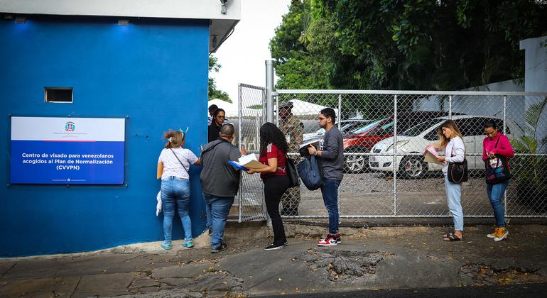 Migrantes venezolanos haciendo fila arriba reciben visa de regularización otorgada en República Dominicana.